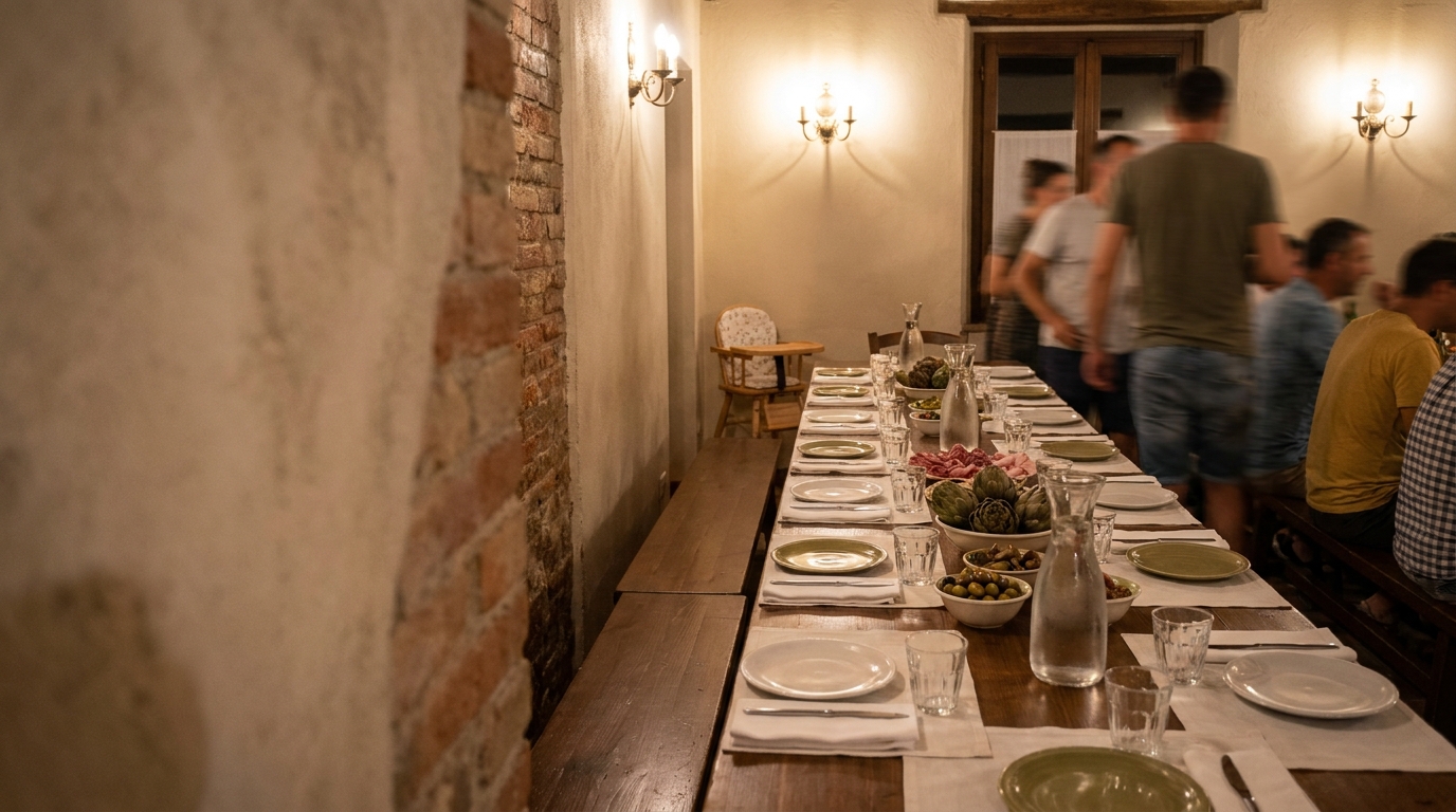 Langer gedeckter Holztisch in der Trattoria mit Antipasti-Schalen, Weingläsern und einem Kinderstuhl am Tischende